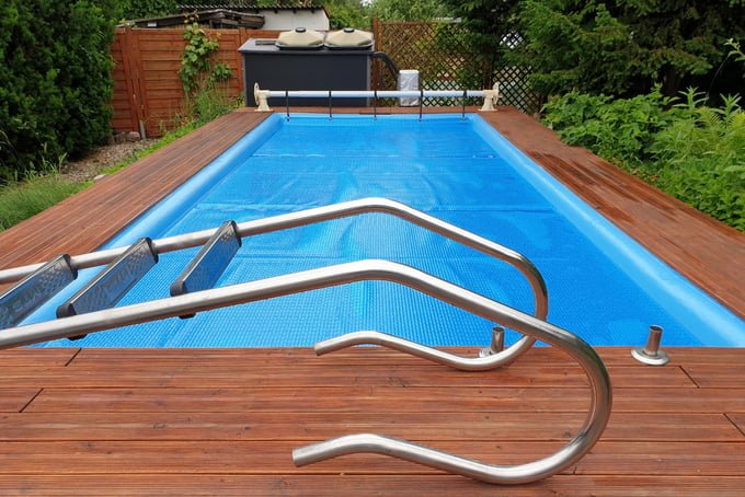 Solar pool cover on outdoor swimming pool with metal steps