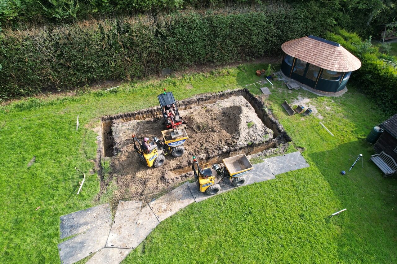 A new swimming pool being dug out of a garden with industrial diggers
