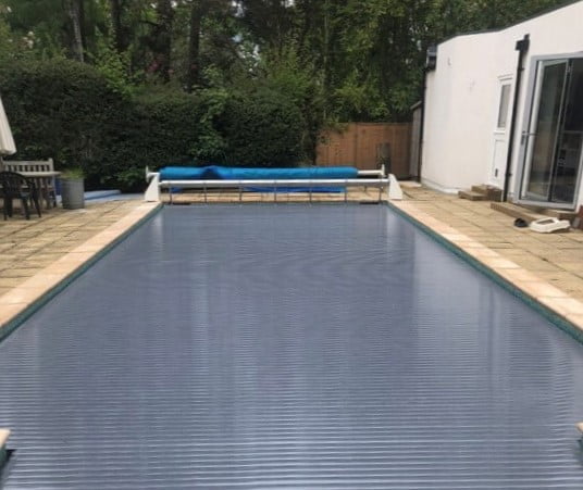 Grey slatted swimming pool cover on an outdoor swimming pool