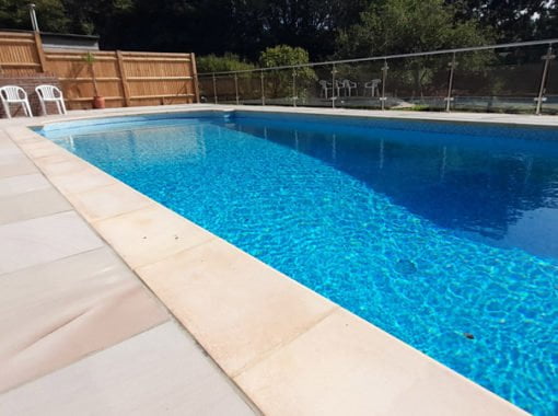 Outdoor swimming pool with patio surround and glass fencing