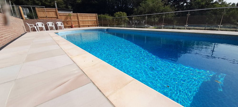 Outdoor swimming pool with patio surround and glass fencing