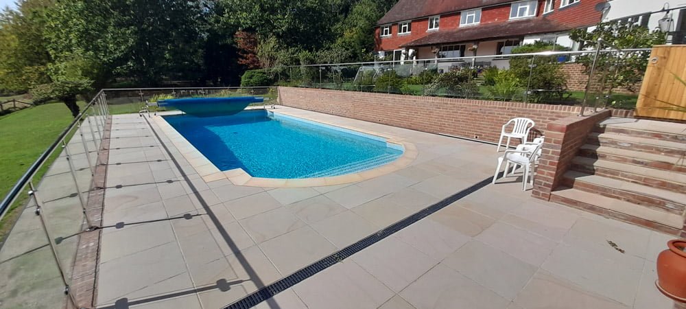 Swimming pool with pool cover, patio and glass surround