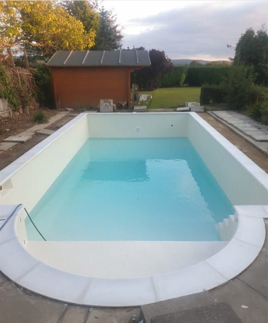 White fibreglass swimming pool half full with water