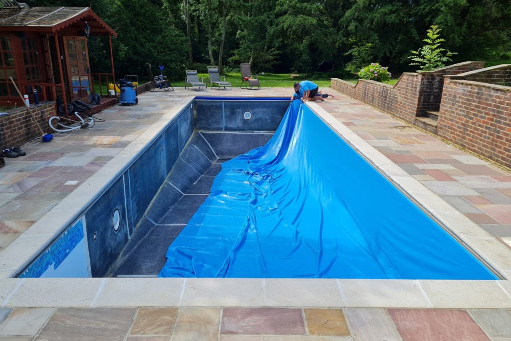 Outdoor swimming pool having a pool liner installed by two men