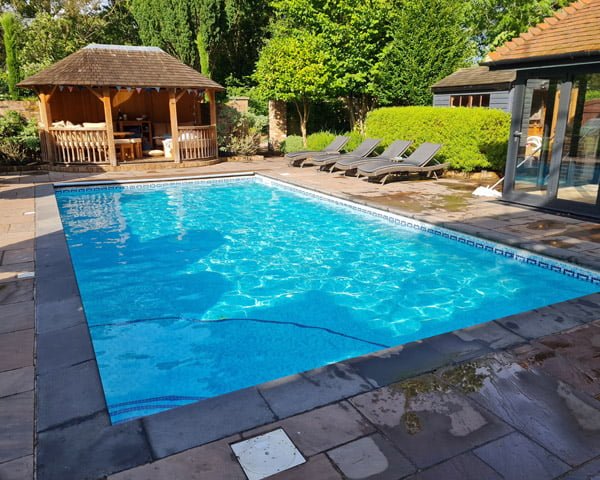 Outdoor swimming pool with wooden outbuilding and patio