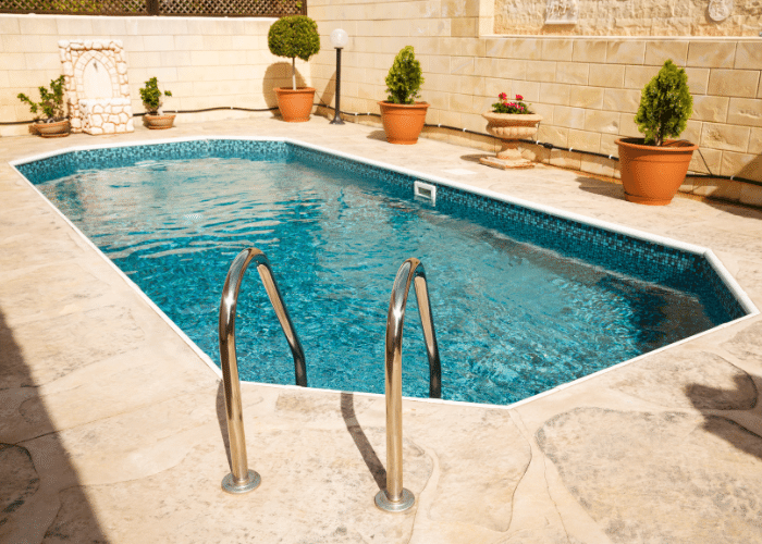 Octagon shaped swimming pool surrounded by plants in pots with steps down into it