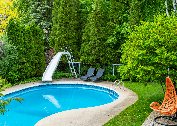 Kidney shaped swimming pool with slide and outdoor seating