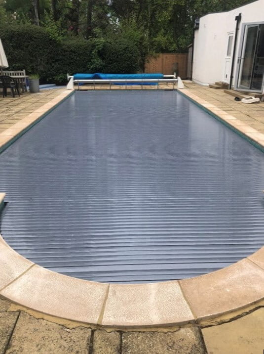 Grey slatted swimming pool cover on an outdoor swimming pool
