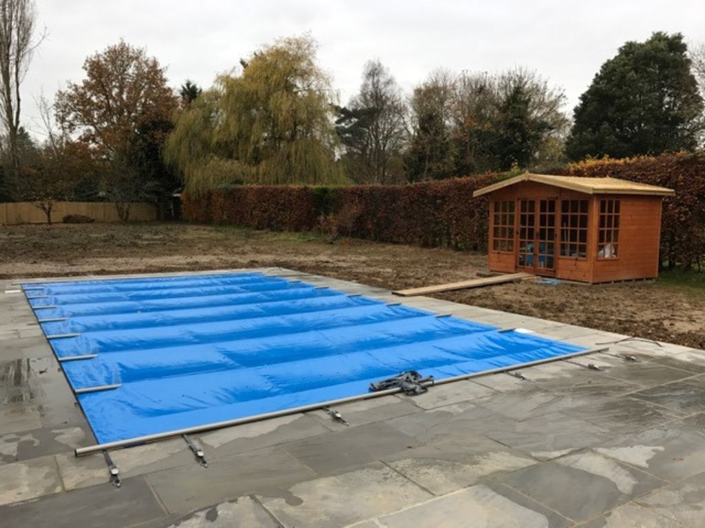 Light blue swimming pool cover with shed in the garden