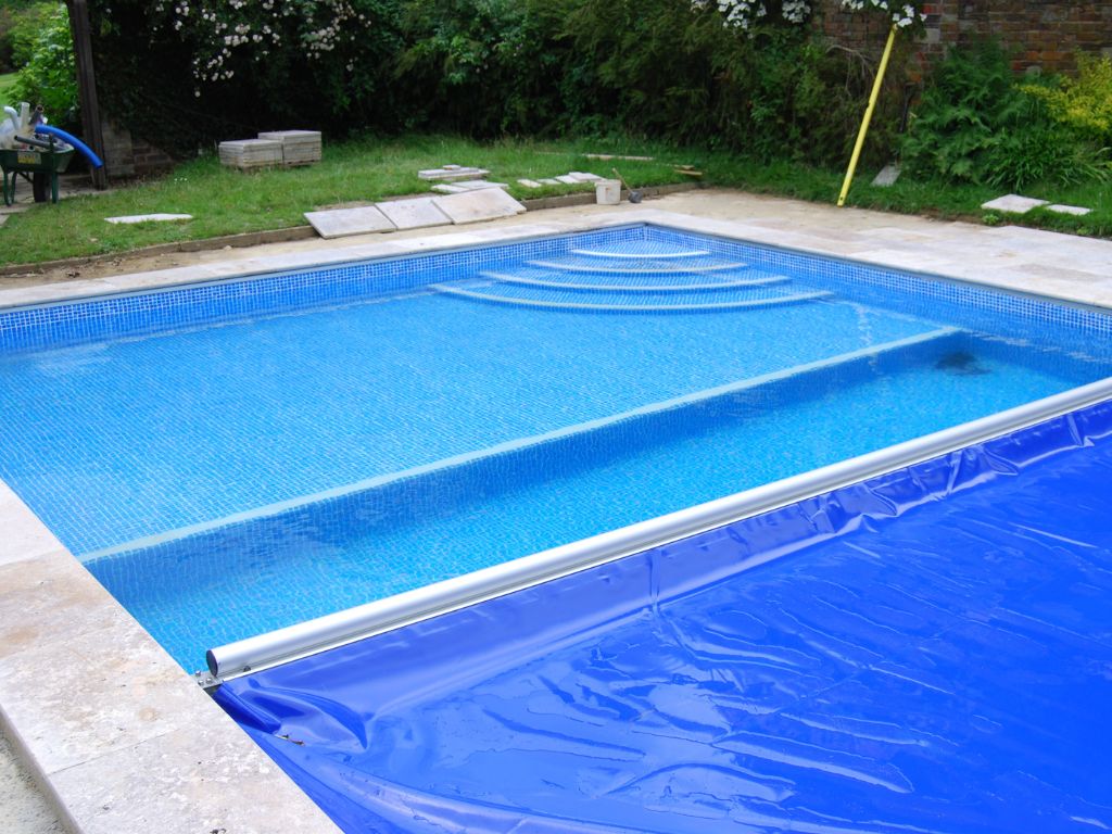 Pool safety cover being removed and showing part of the swimming pool