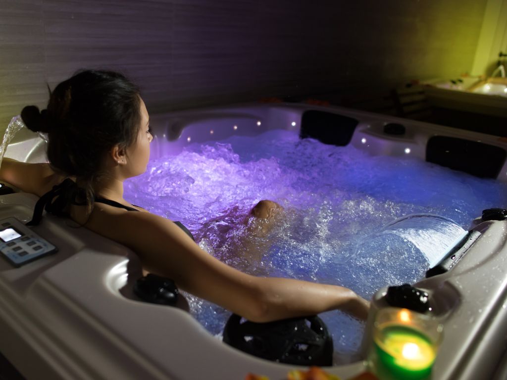 Woman relaxing in a hot tub with colour changing lights