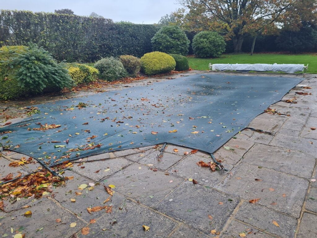Green winter debris swimming pool cover with leaves on it