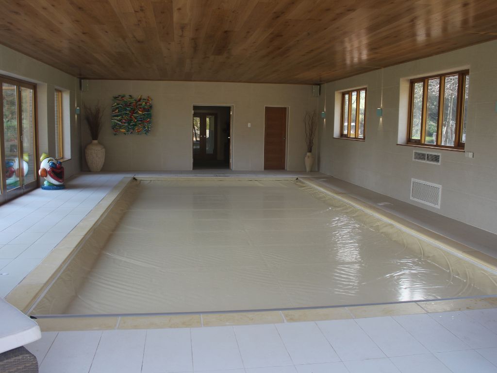 Cream pool safety cover on an indoor swimming pool