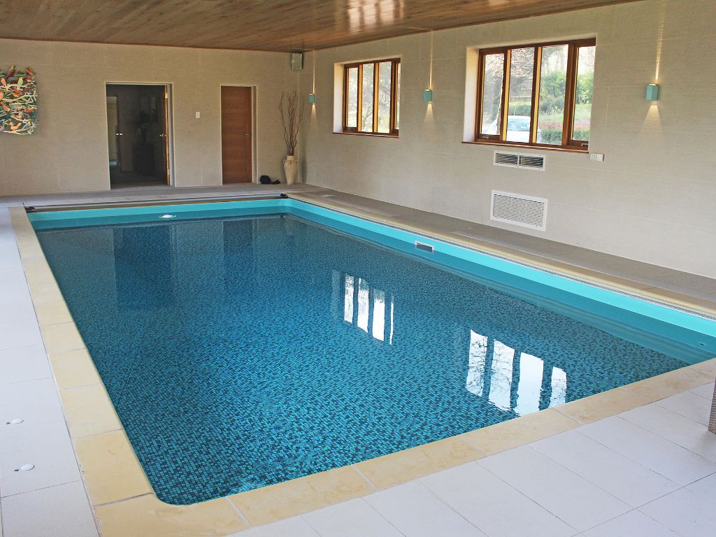 Indoor swimming pool in cream room with wooden ceiling