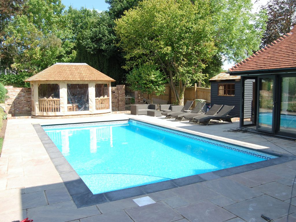 A rectangle outdoor swimming pool with a wood outbuilding