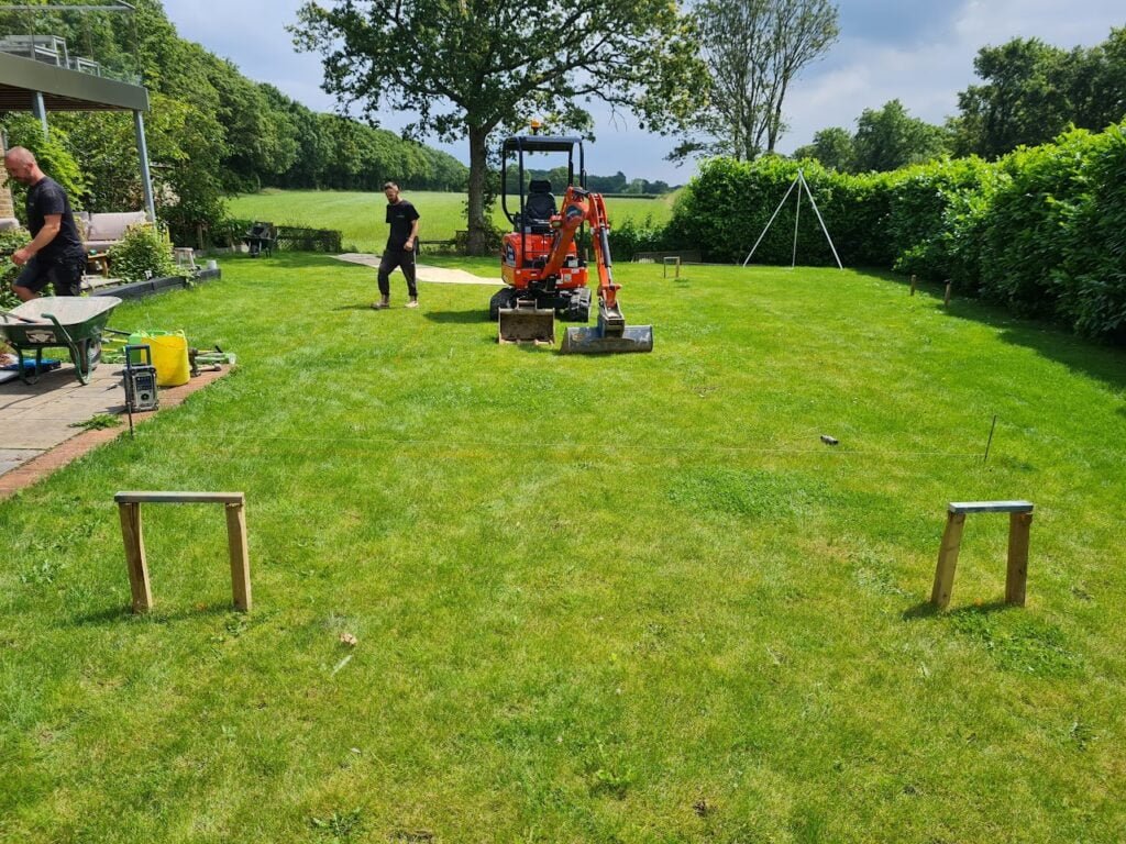 A digger about to start digging a rectangle pool in a back garden