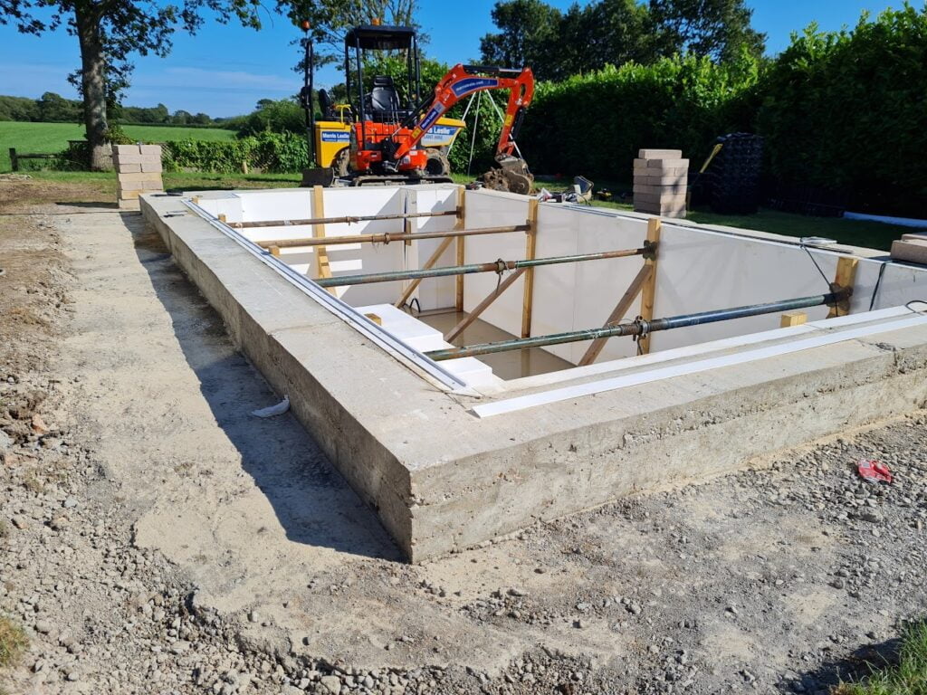 Swimming pool foundations for an outdoor swimming pool with a digger in the background