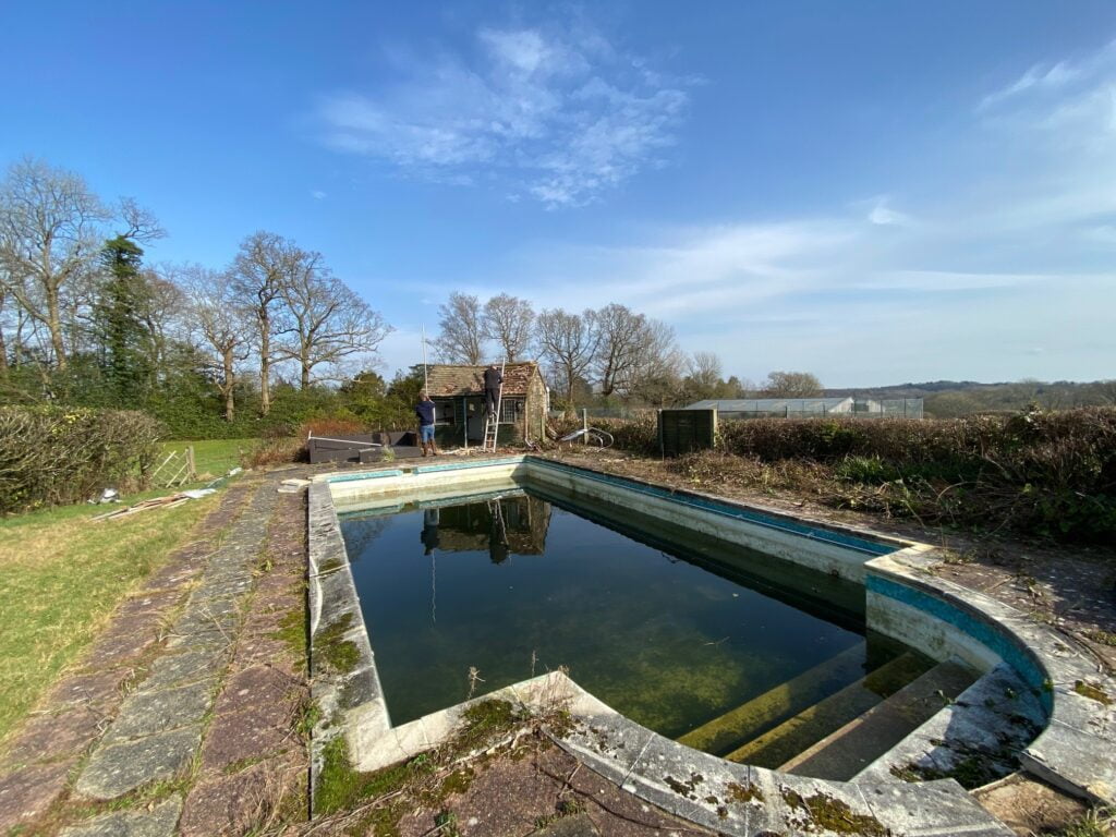 Neglected swimming pool with green water and moss