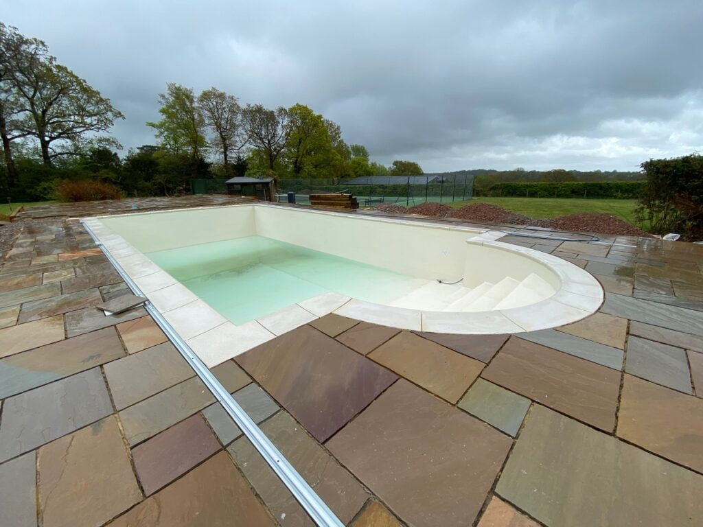 An empty outdoor swimming pool with surrounding patio