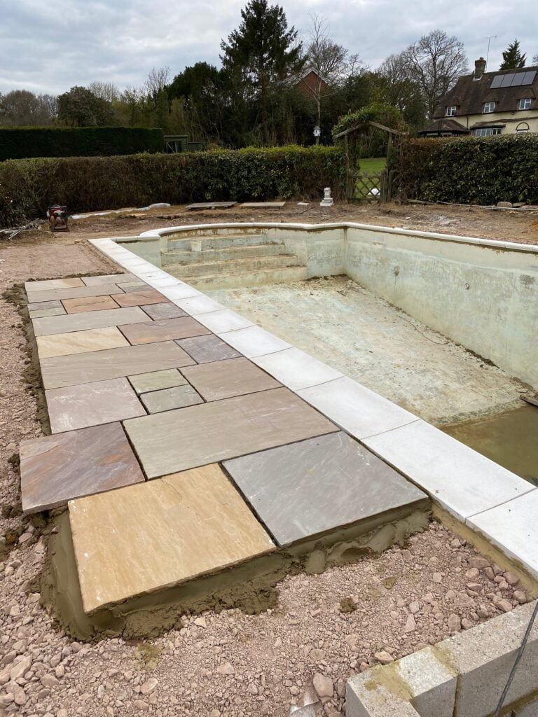 An outdoor pool mid refurbishment with patio being laid