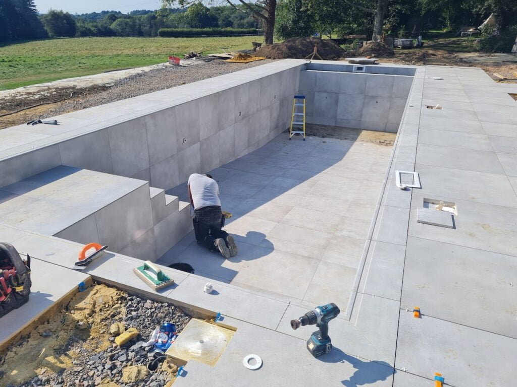 An outdoor swimming pool under construction with a man working