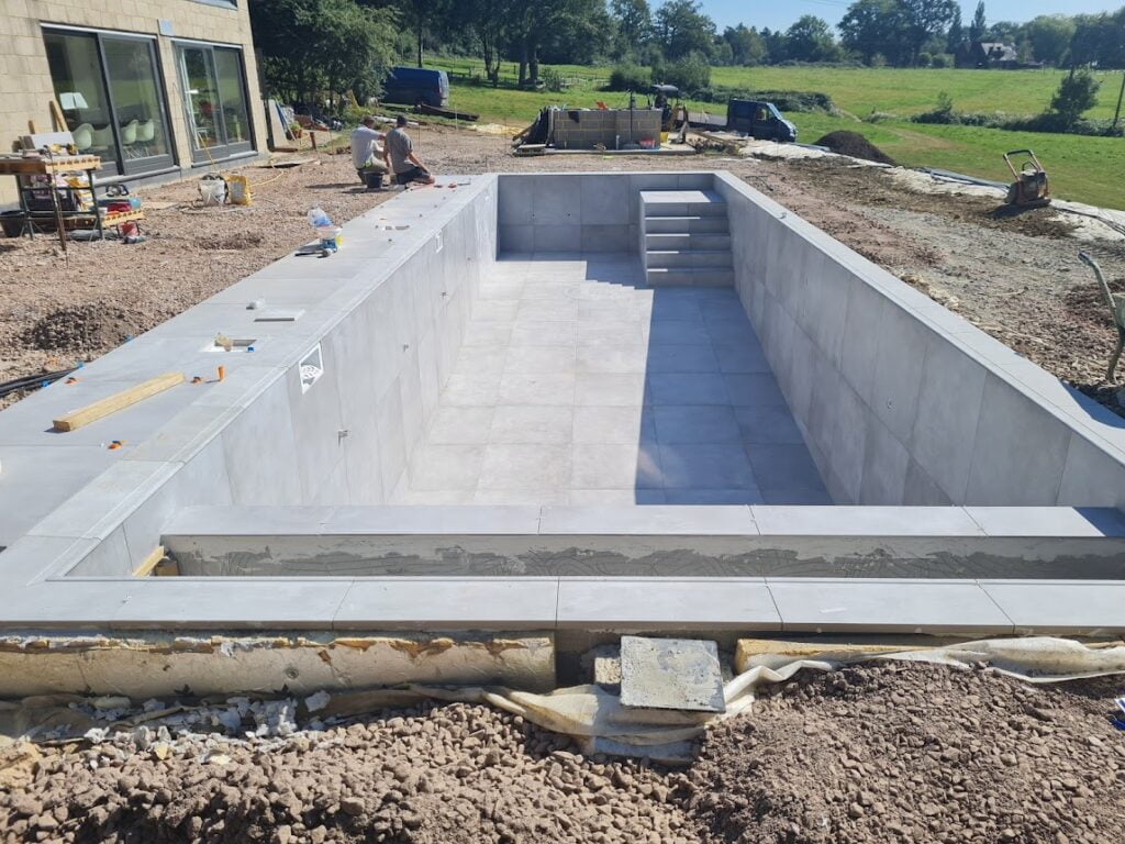 An outdoor swimming pool under construction with two men working