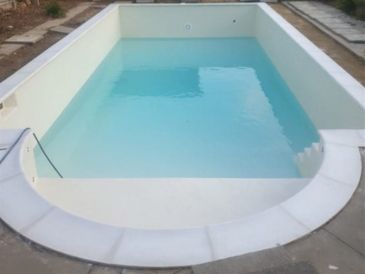 White fibreglass swimming pool half full with water