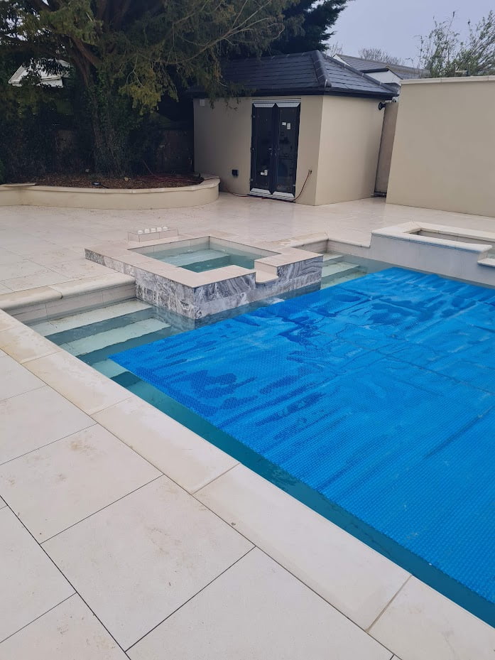 Rectangle swimming pool with small square spa on the end and a blue pool cover
