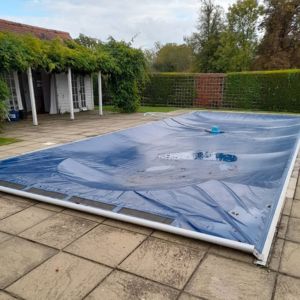 Professionally installed blue winter debris pool cover on a rectangle pool
