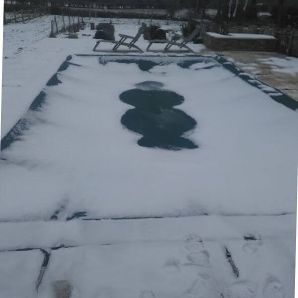 Snowy swimming pool with a pool cover on