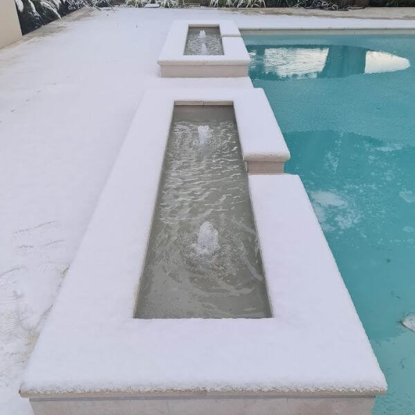 Frozen swimming pool with snow surrounding it