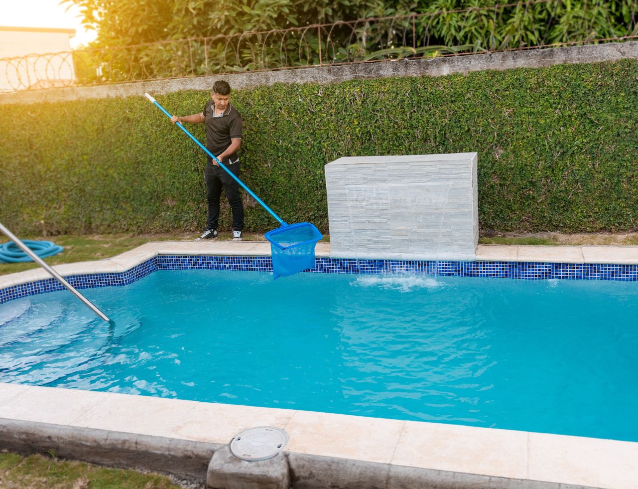 man cleaning outdoor swimming pool