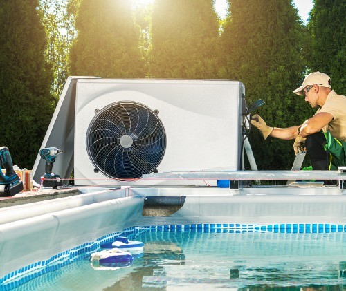 man installing a heat pump for a swimming pool