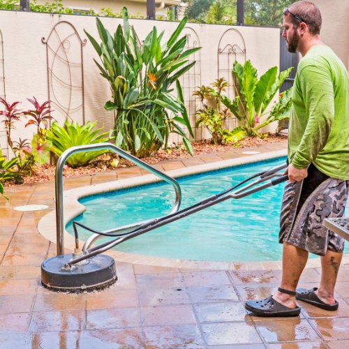 man cleaning garden patio next to pool