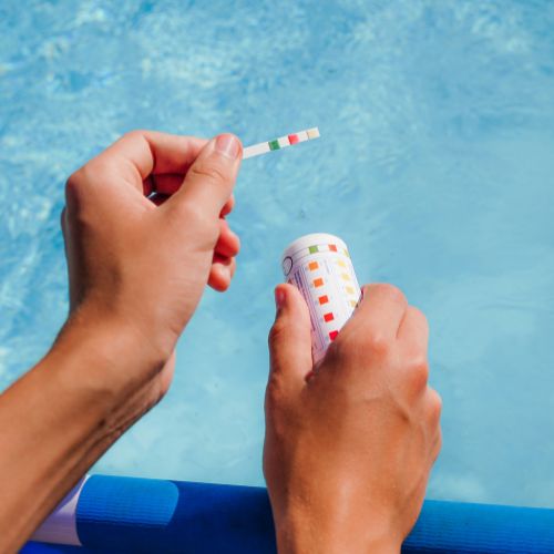 person testing ph of pool with test strips