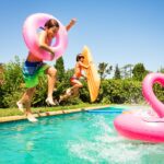 kids jumping into swimming pool with floats