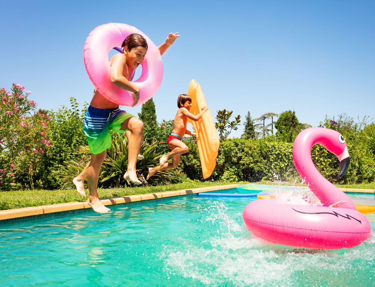 kids jumping into swimming pool with floats
