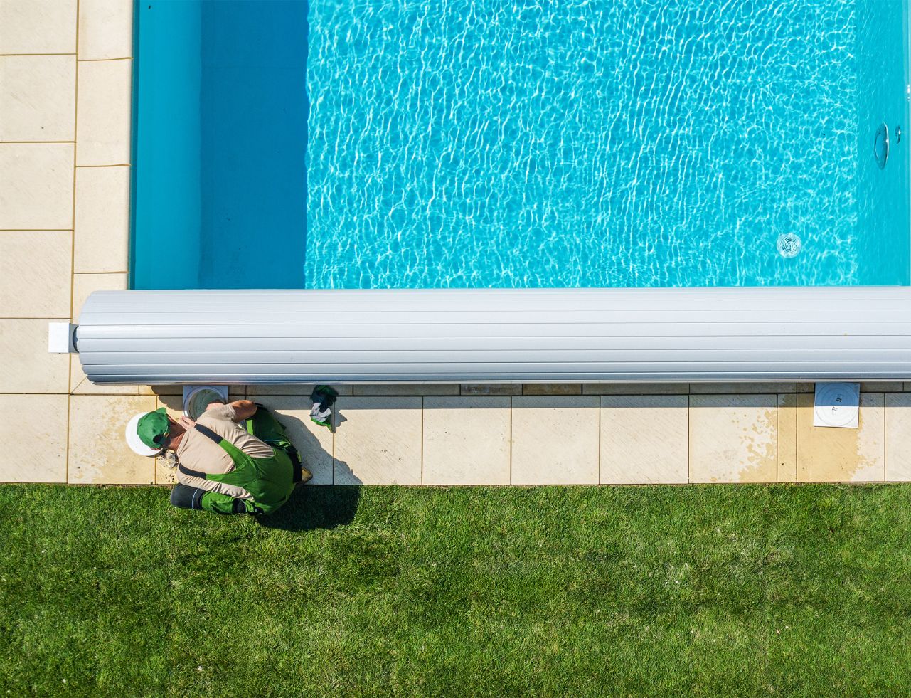 pool maintenance man working on pool cover